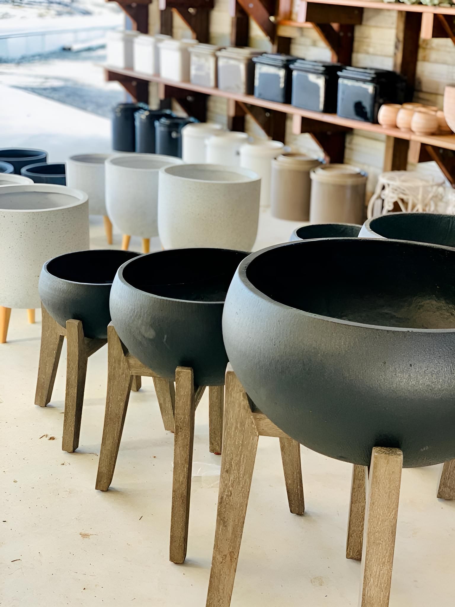 A Row of Pots on Wooden Legs in a Store — Black Rock Garden Centre In Tyagarah, NSW
