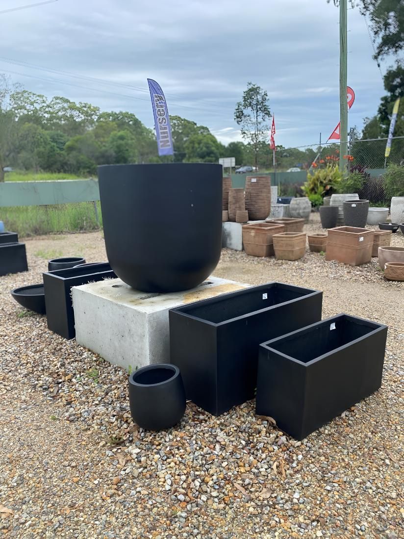 A Bunch of Black Pots Are Sitting on Top of a Pile of Gravel — Black Rock Garden Centre In Tyagarah, NSW