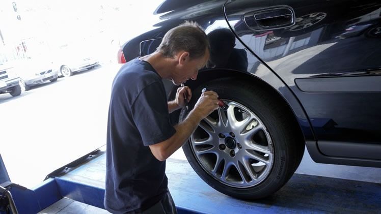 A man is working on a car wheel in a garage