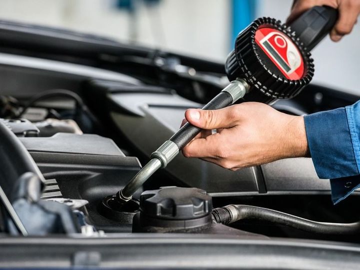 A man is pouring oil into a car with a pump.