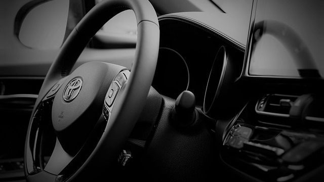 A black and white photo of the steering wheel of a car.