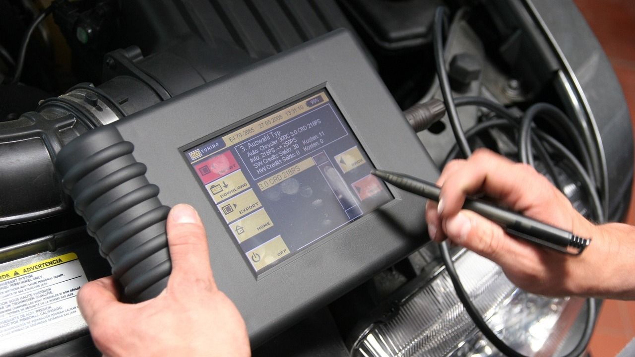 A person is using a computer to check the engine of a car.