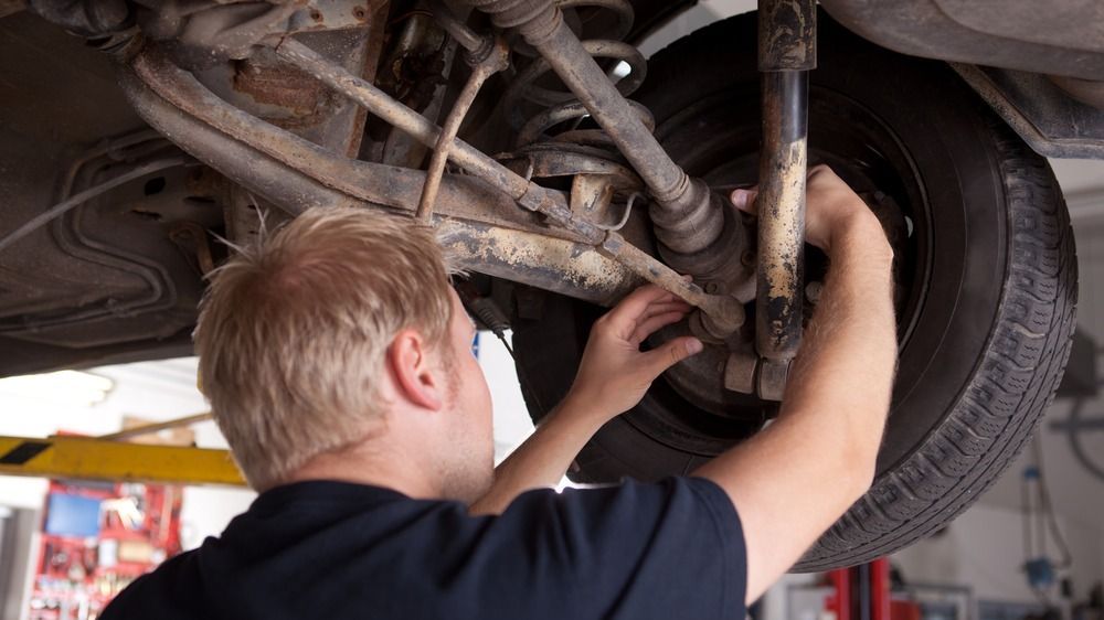 A man is working on the underside of a car in a garage.