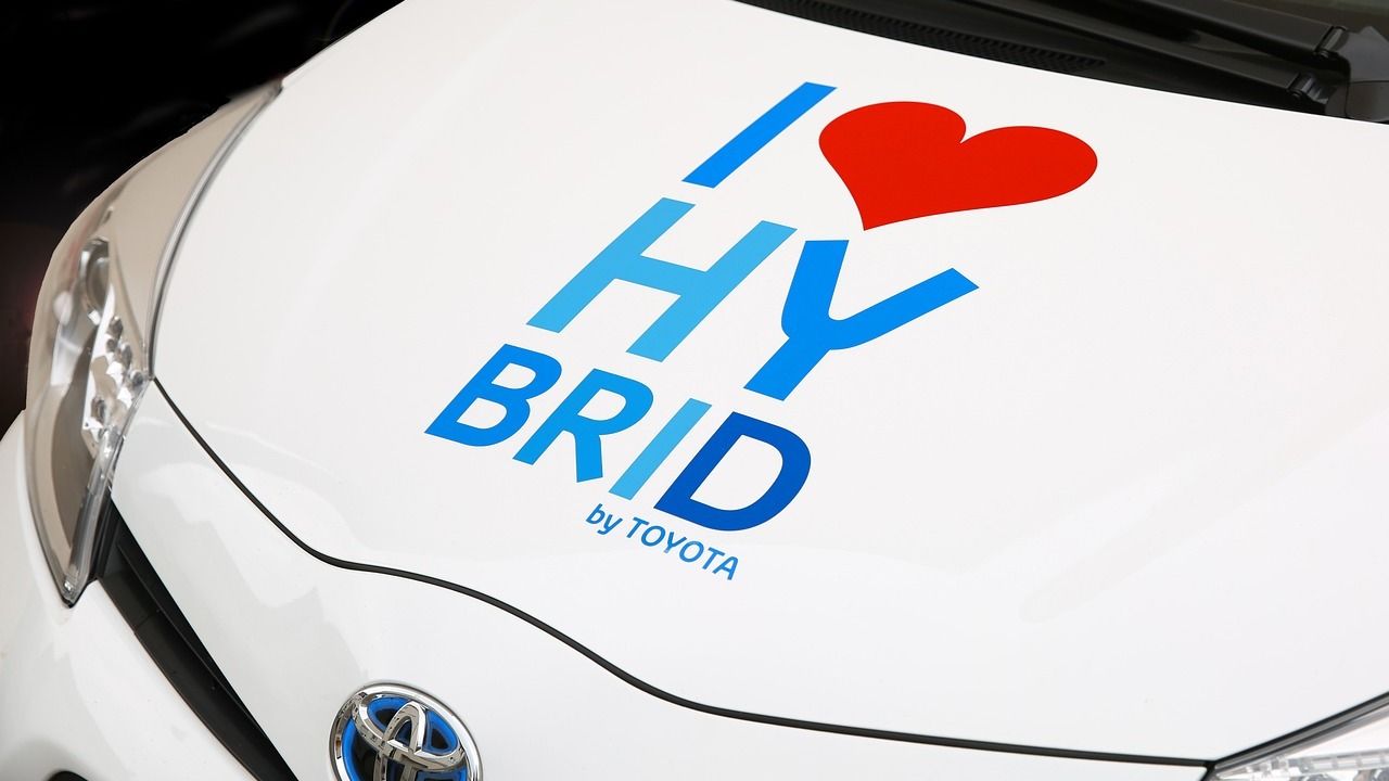 A white toyota hybrid car with a heart on the hood.