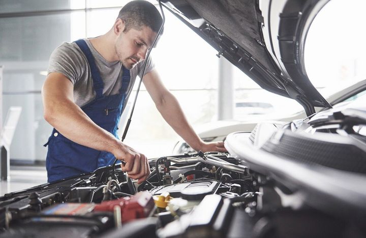 A man is working on the engine of a car in a garage.