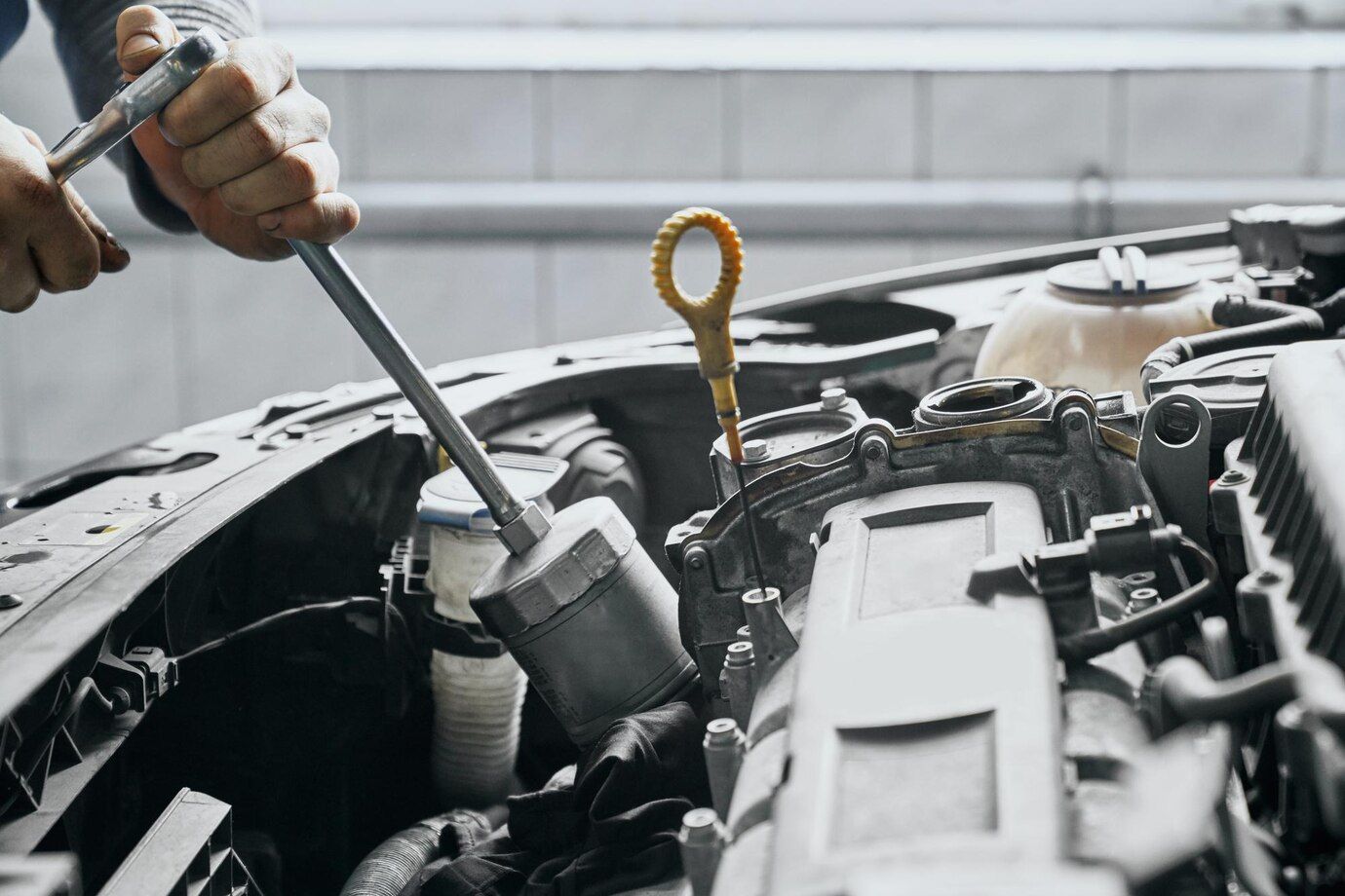 A man is working on a car engine with a wrench.