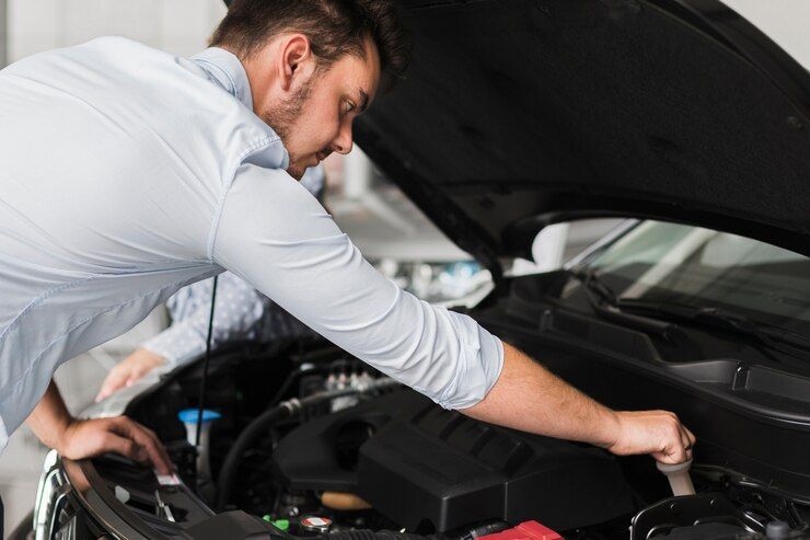 A man is working on the engine of a car with the hood open.