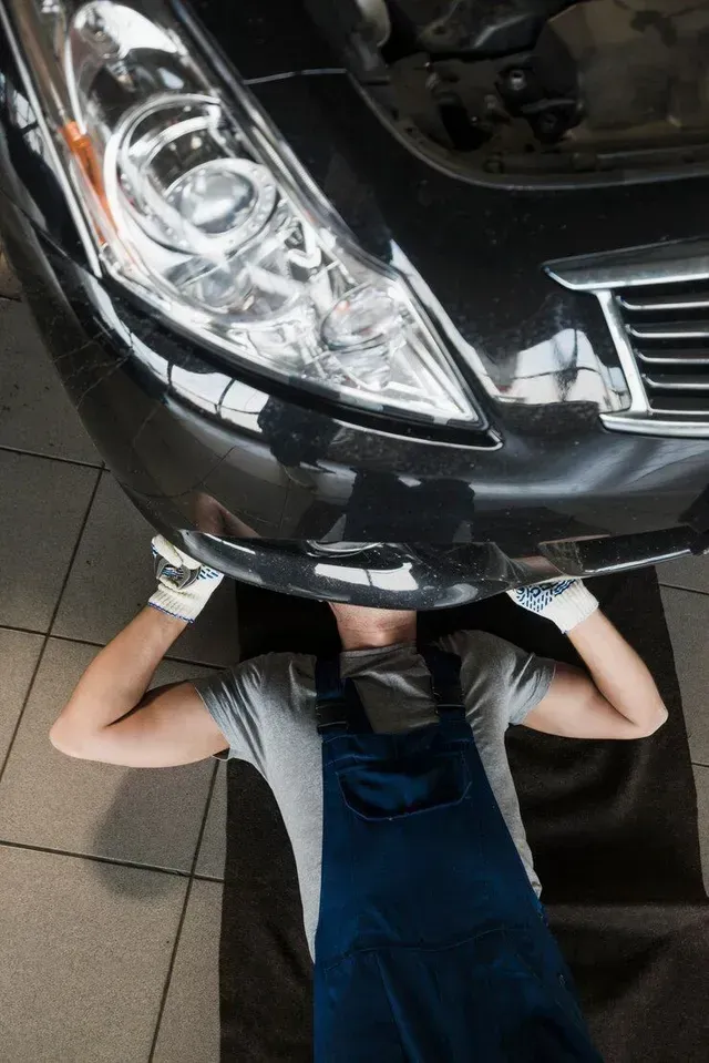 A man is laying under a car in a garage.