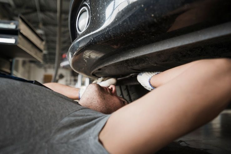 A man is laying under a car in a garage.