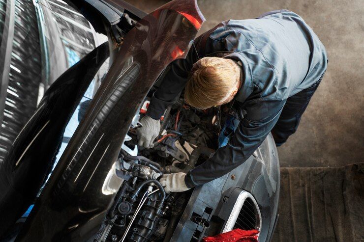 A man is working on the engine of a car in a garage.