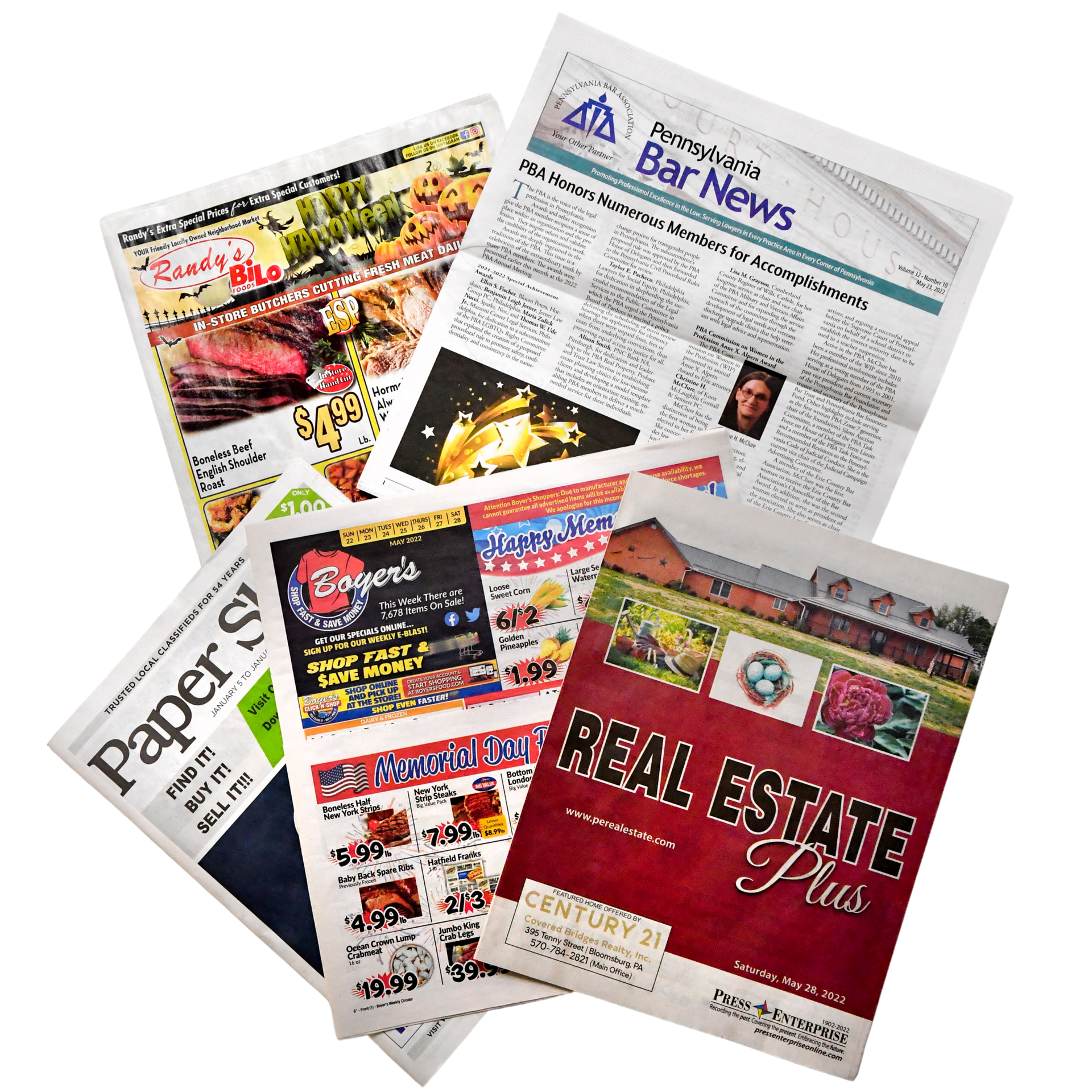 A bunch of newspapers including one that says real estate plus