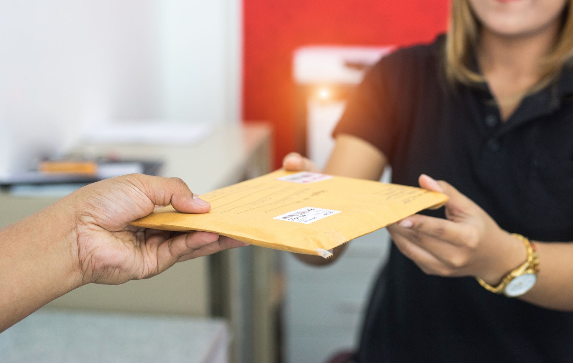 Handing a yellow envelope from one person to another in an office setting