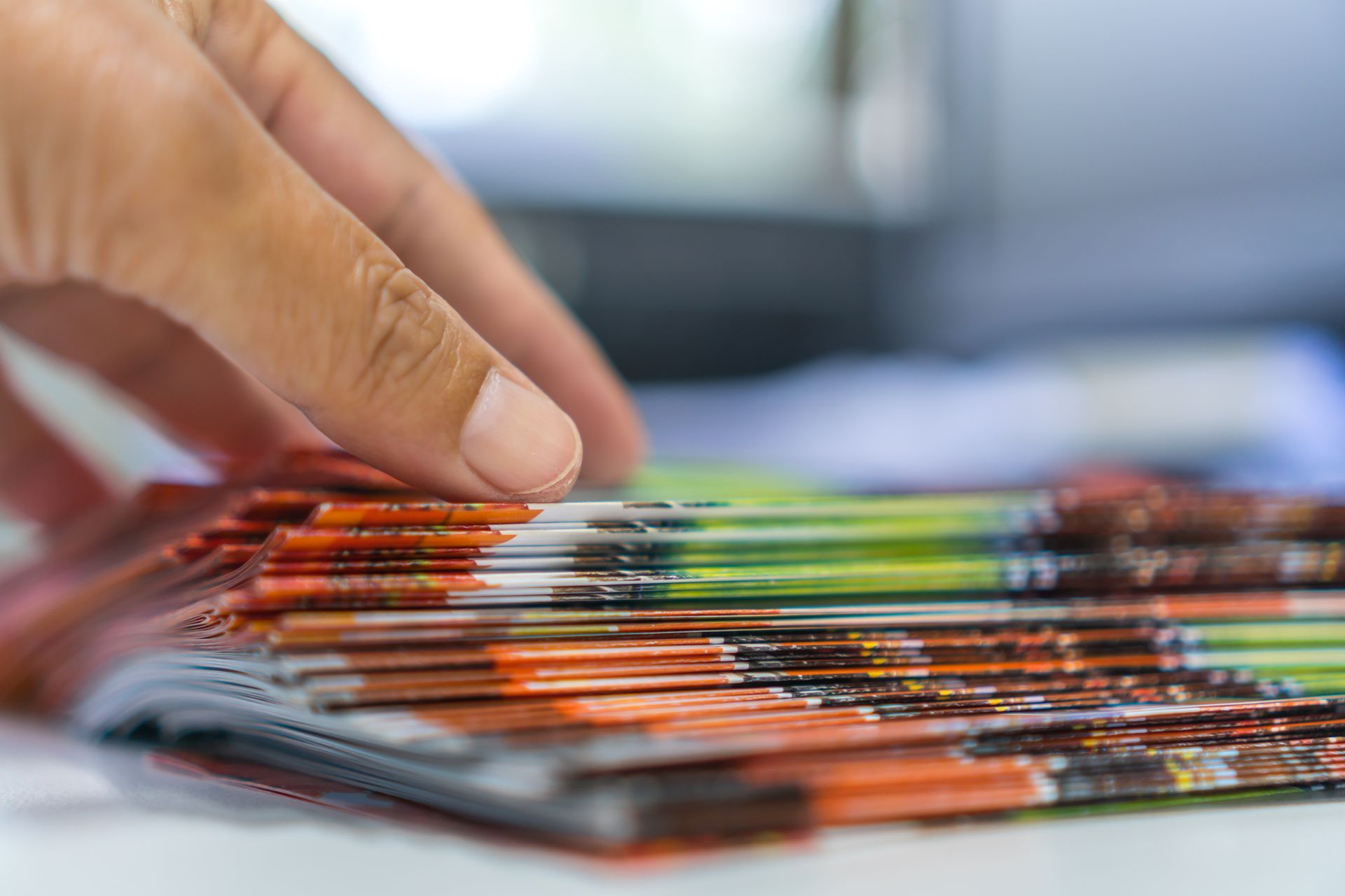 Hand reaches for a stack of colorful brochures, freshly printed.