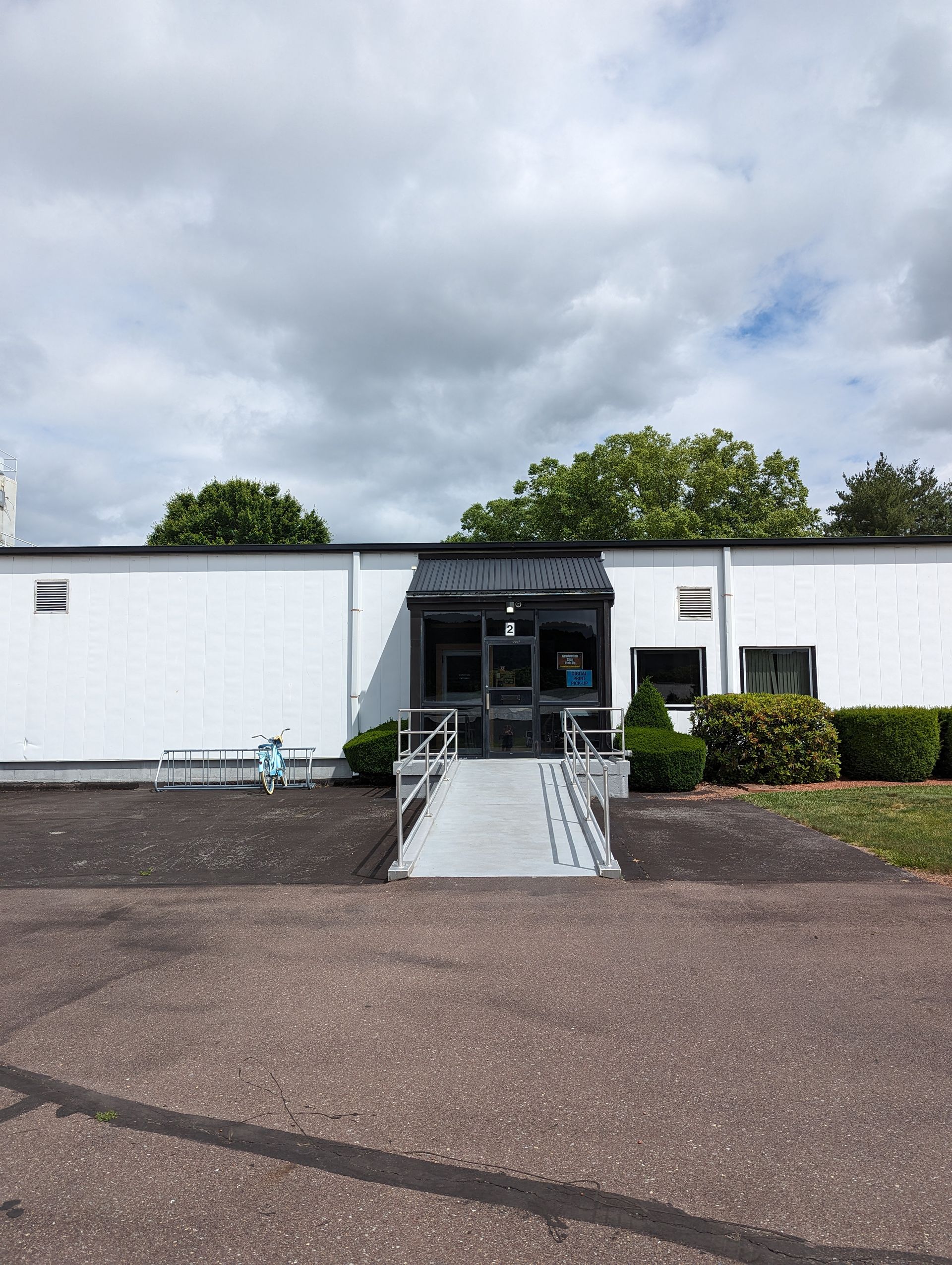 A white building with a ramp leading to the front door Press Enterprise Commercial Printing Icon