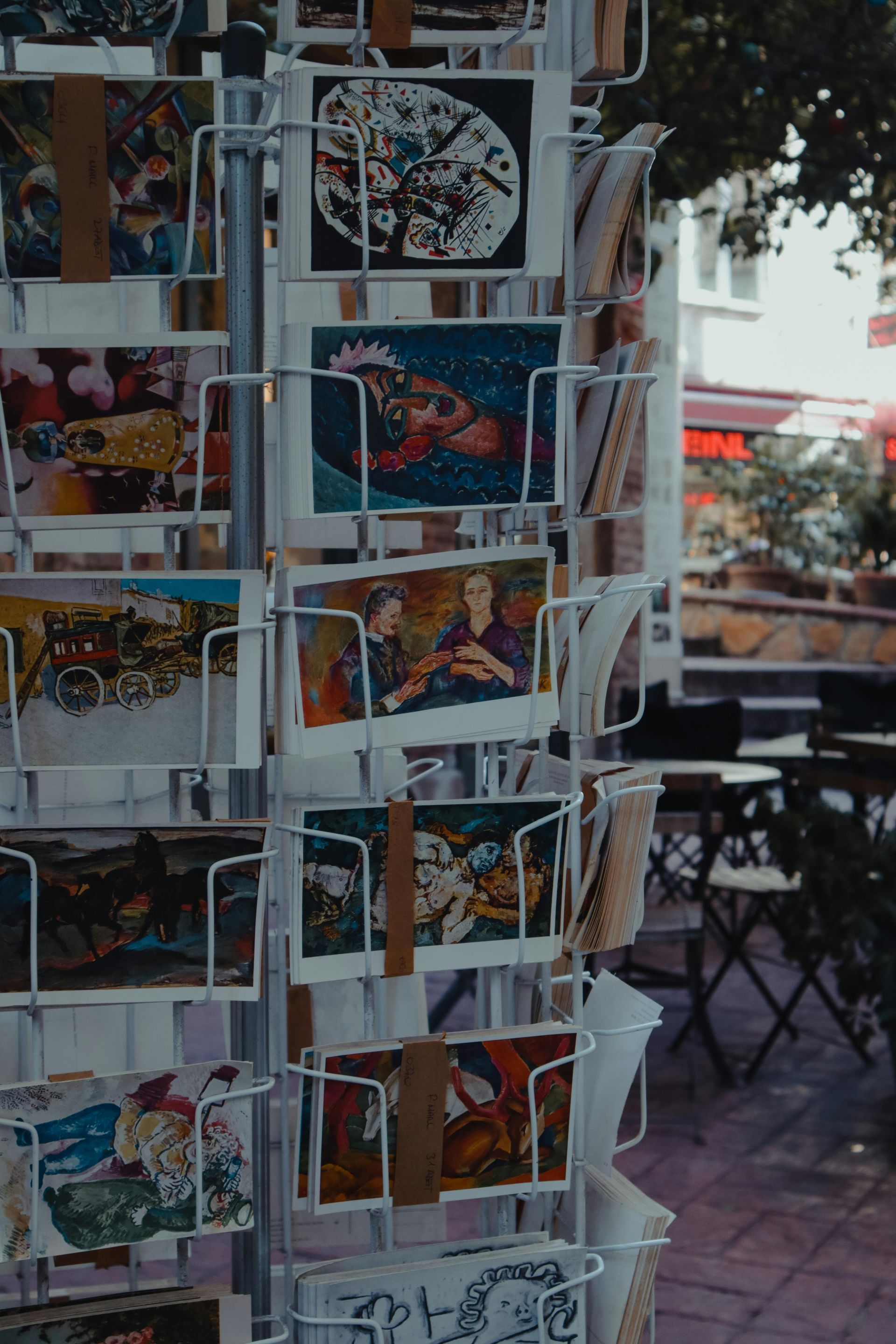 A bunch of postcards are hanging on a rack.