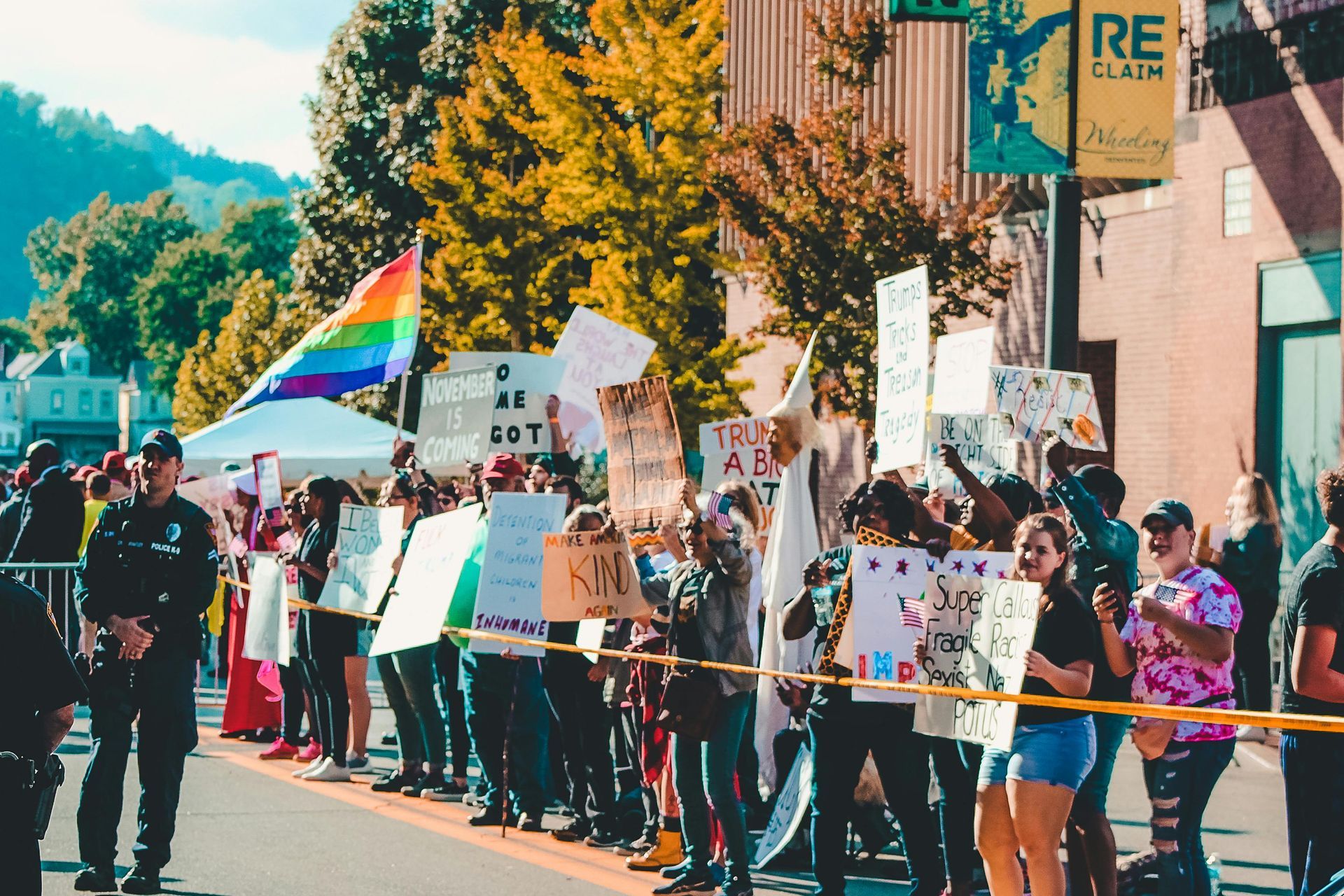 A group of people are holding signs and a rainbow flag.