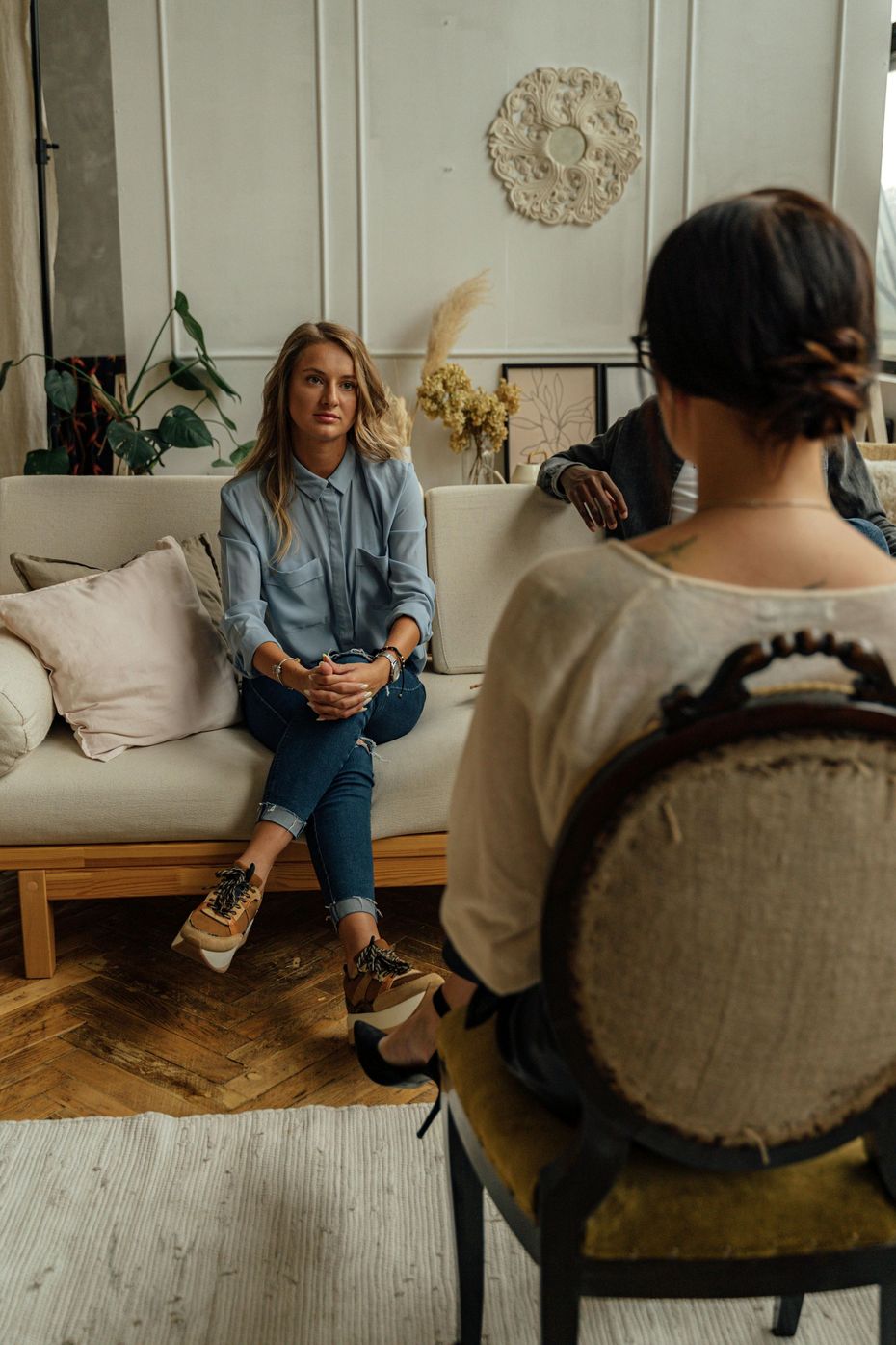A man and a woman are sitting on a couch talking to a woman.