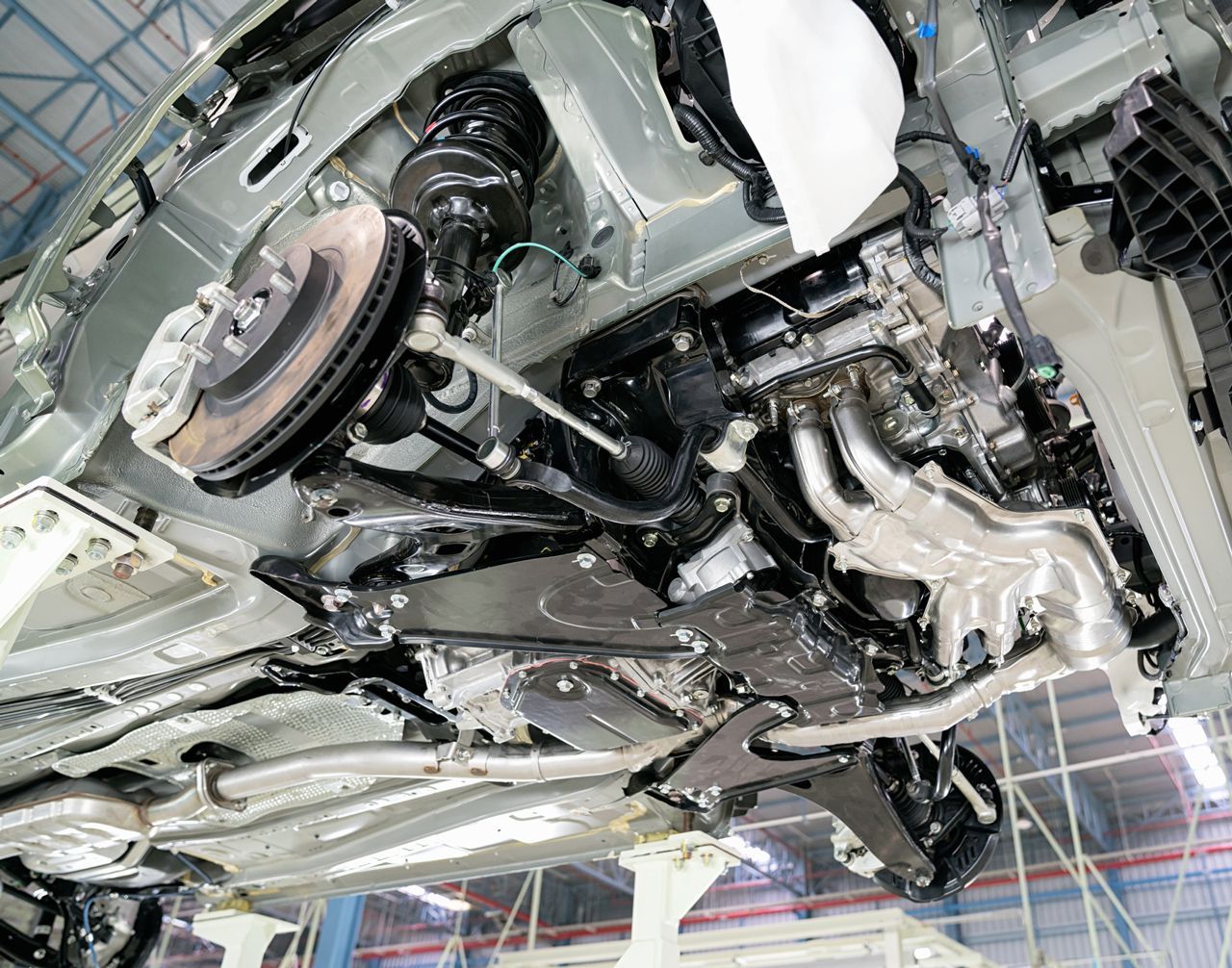 A close up of the underside of a car in a factory.