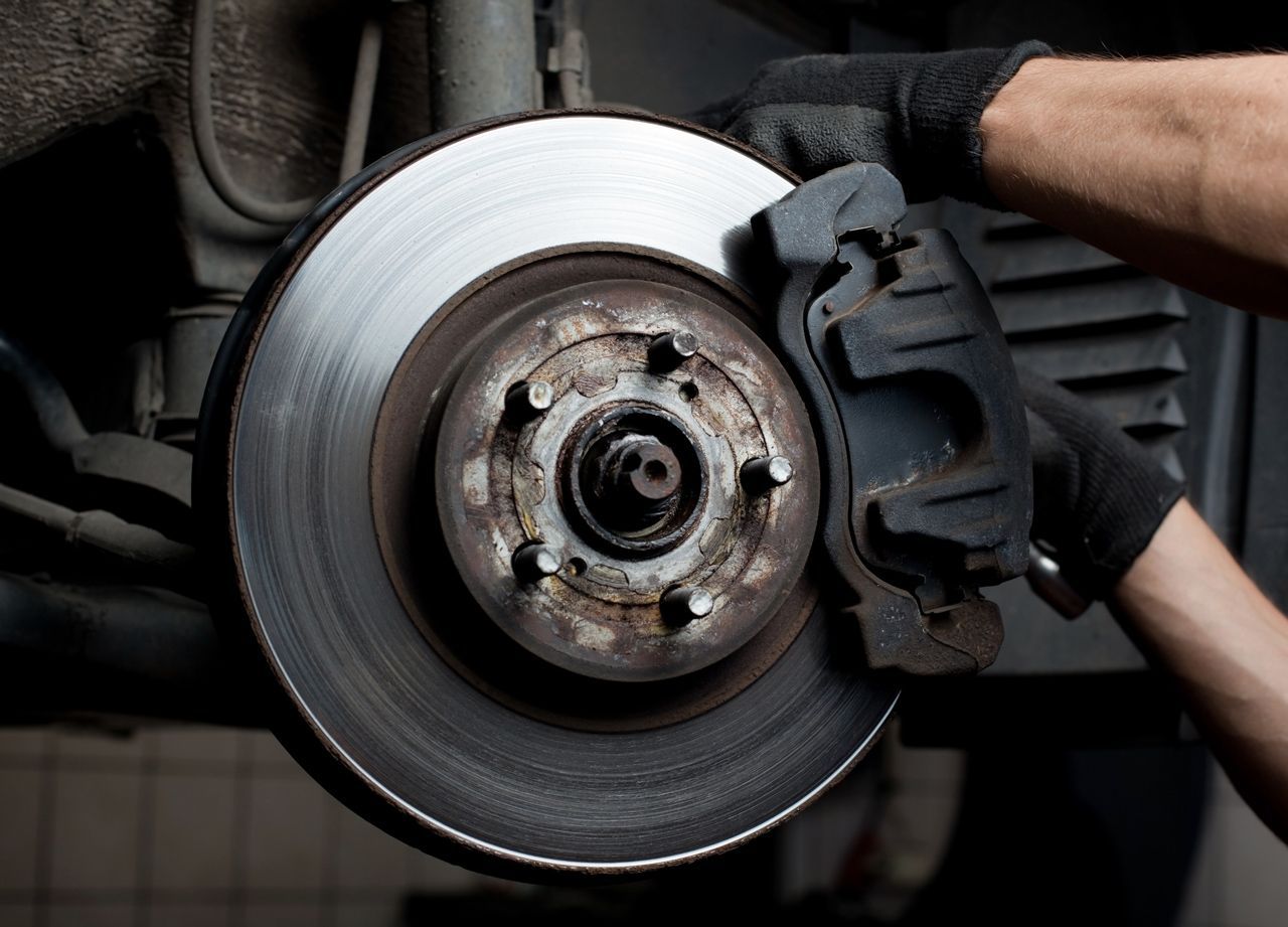 A person is fixing a brake pad on a car.