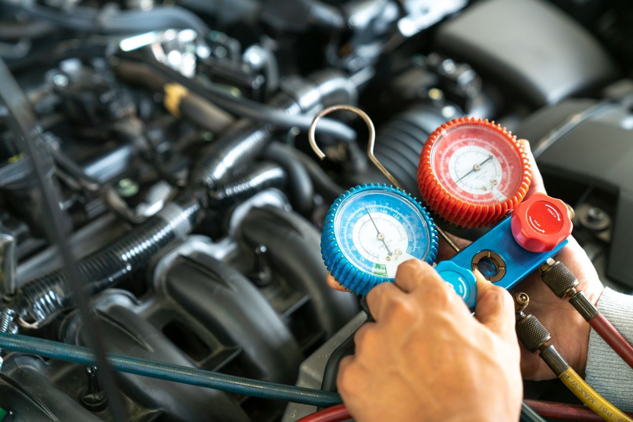 A person is working on a car engine with a gauge.