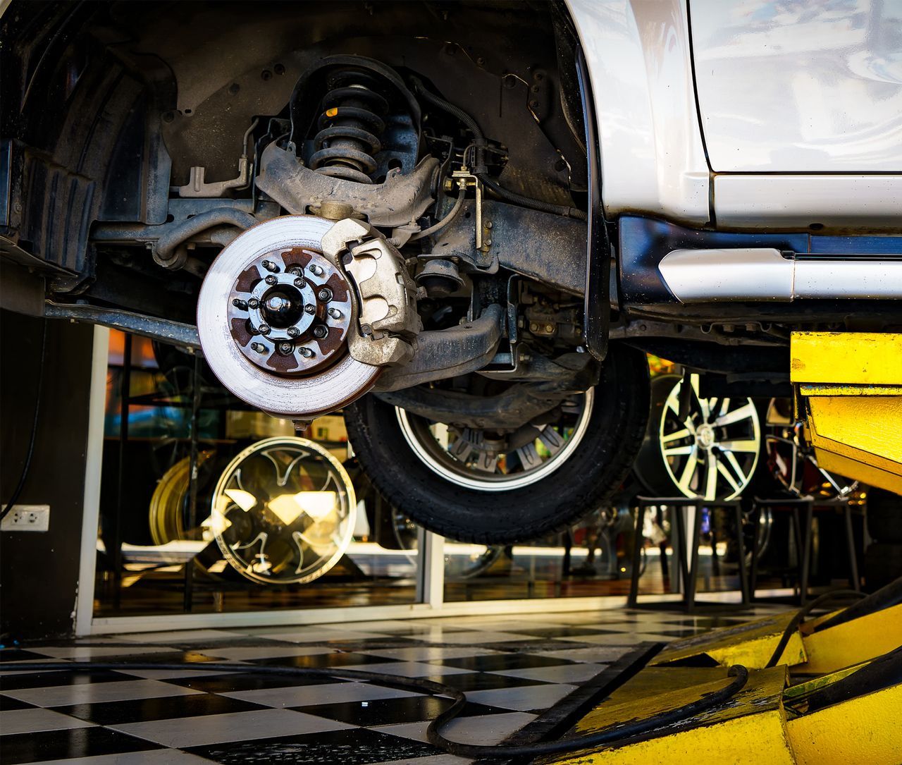 A car is being repaired on a lift in a garage.