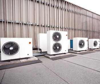 A row of air conditioners are lined up on the roof of a building.