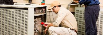 Two men are working on an air conditioner in a room.