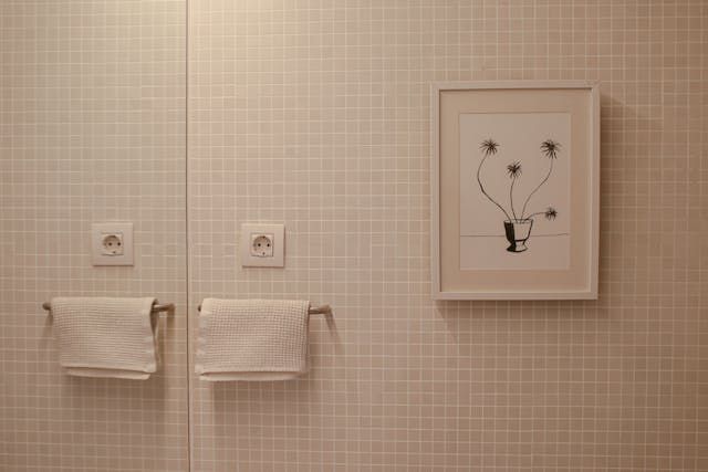 A bathroom with two towels hanging on a towel rack and a picture on the wall.
