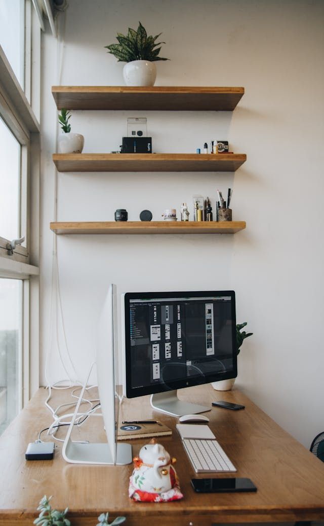 A computer is sitting on a wooden desk next to a window.
