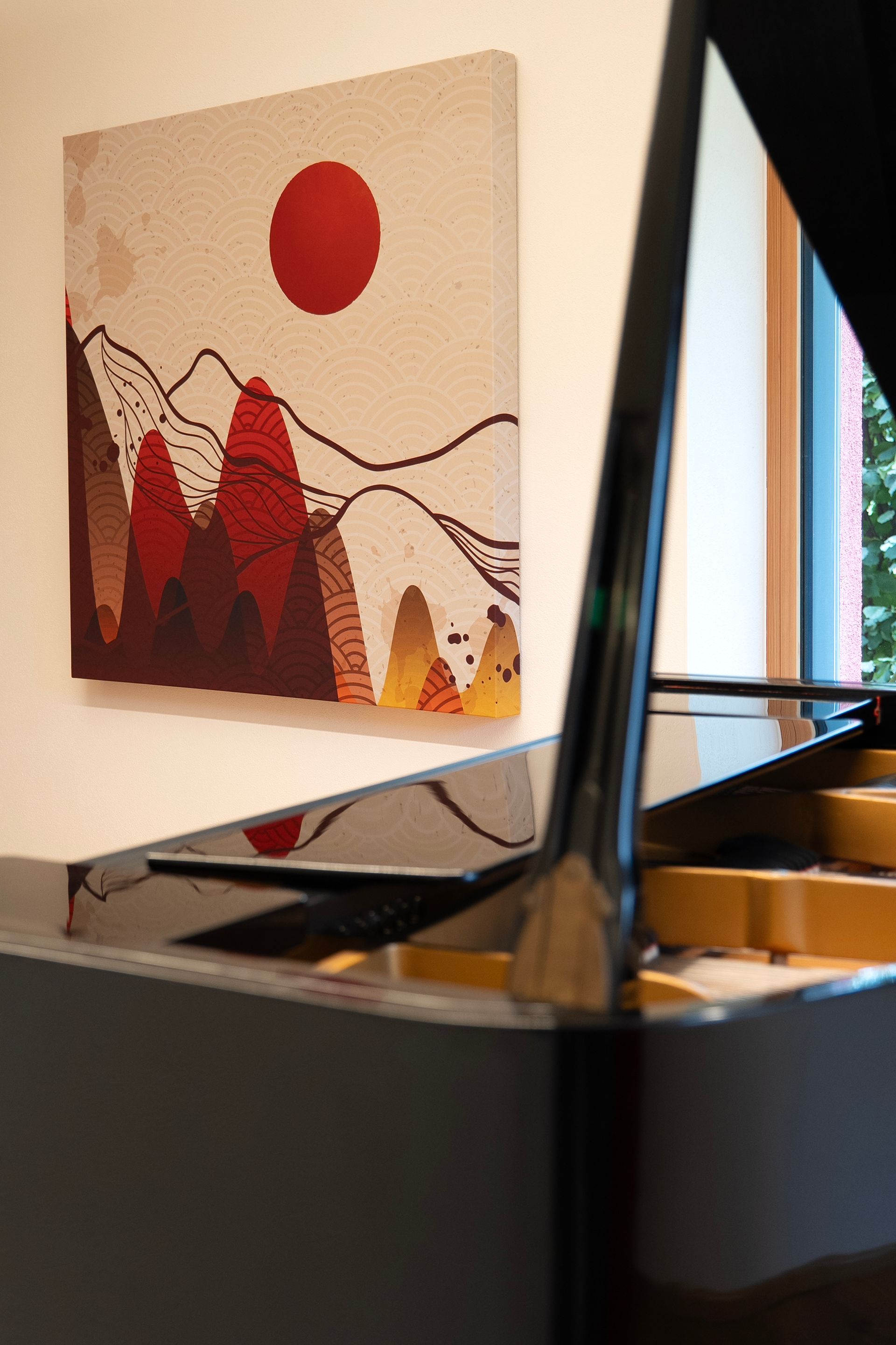 Klavier mit geöffnetem Deckel, in dem sich ein farbenfrohes Landschaftsgemälde mit Bergen und einer roten Sonne spiegelt.