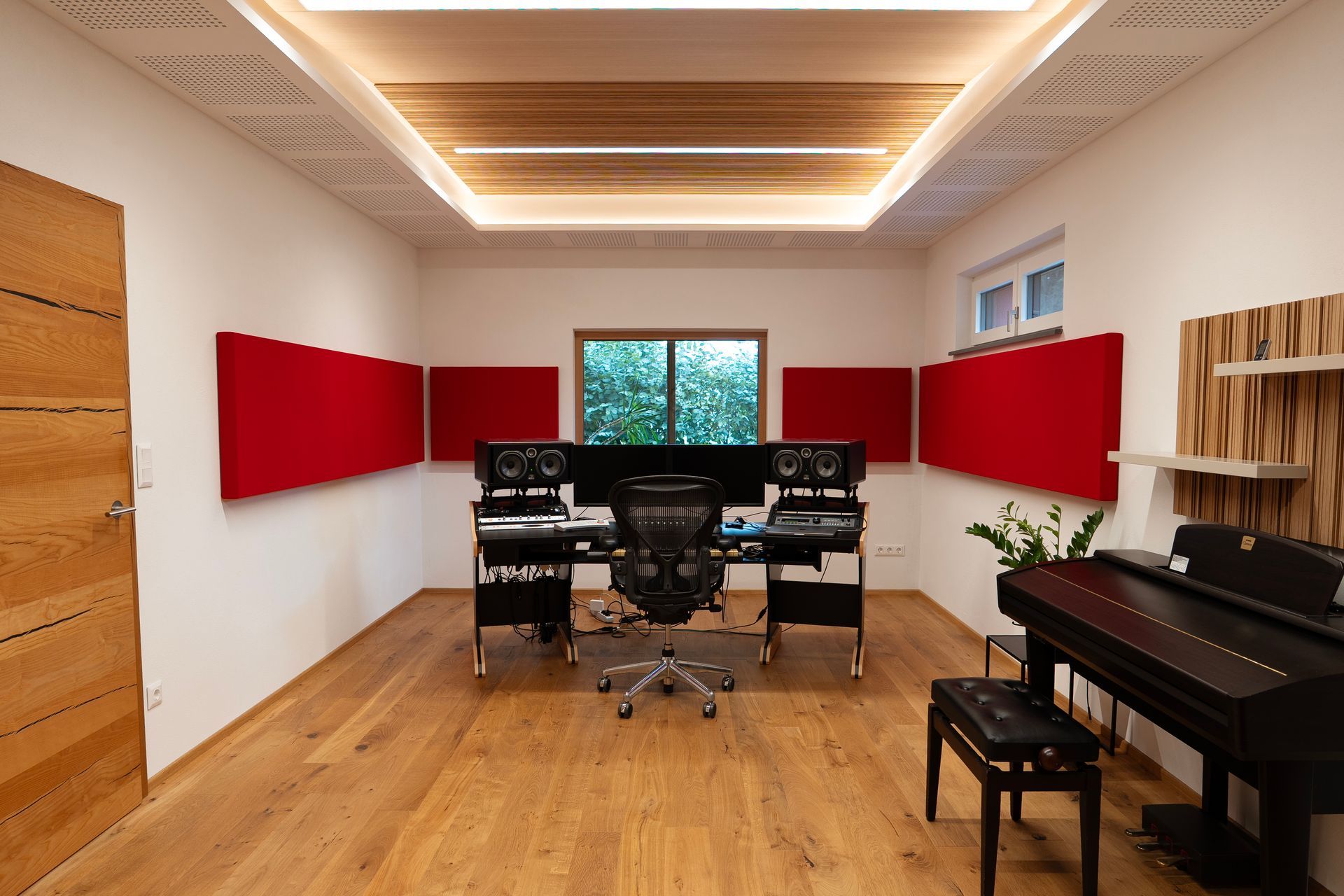 Tonstudio mit roten Akustikpaneelen, Holzelementen an der Decke und einem Klavier.