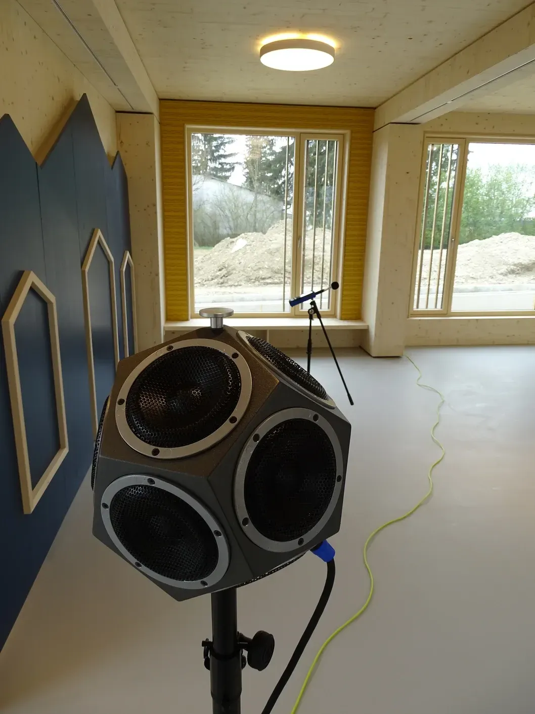 Akustisches Messgerät in einem Raum mit Fenstern und einer blauen Wand.