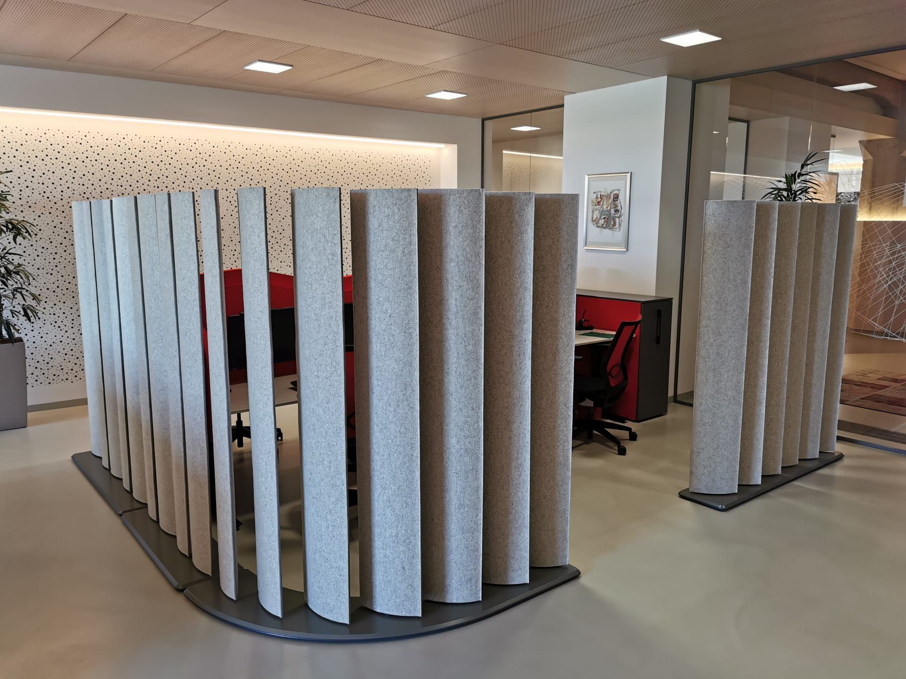 Büroräume mit Akustikwänden, einem Schreibtisch und einer dekorativen Decke.