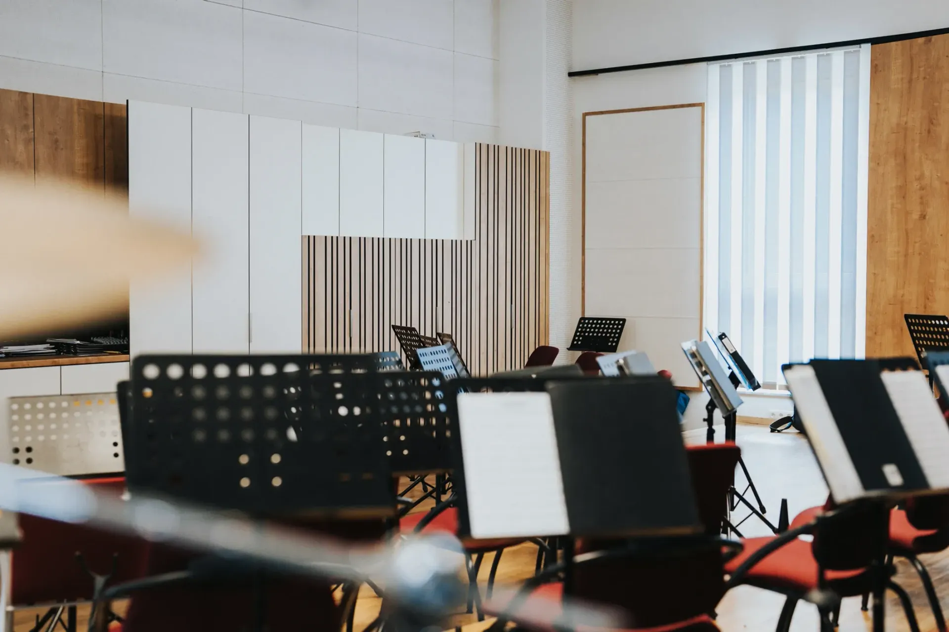 Musikzimmer mit Notenständern, Stühlen und Akustikpaneelen.
