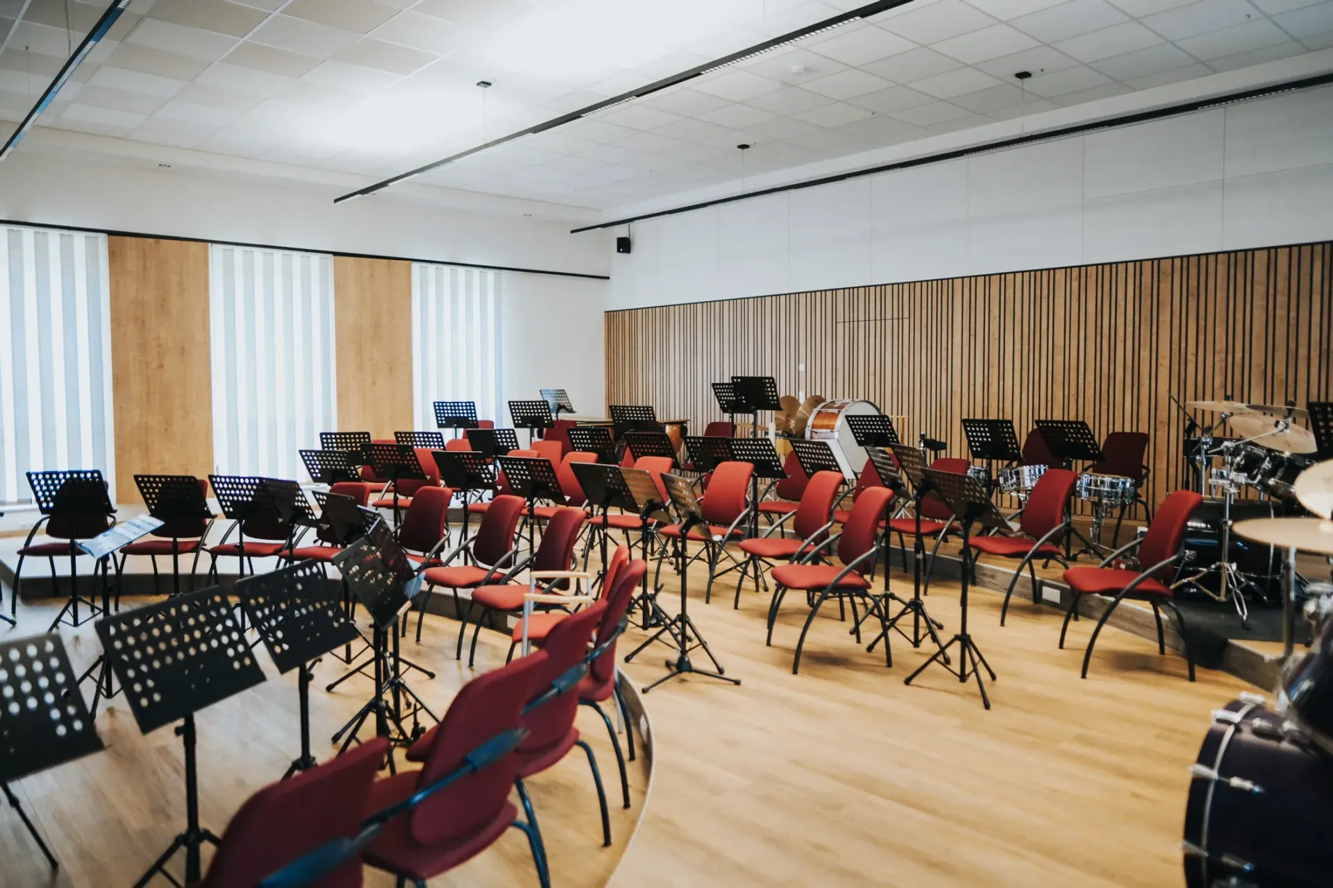 Leerer Probenraum mit Notenständern und Stühlen und Akustikpaneelen, die für ein Orchester aufgestellt sind.