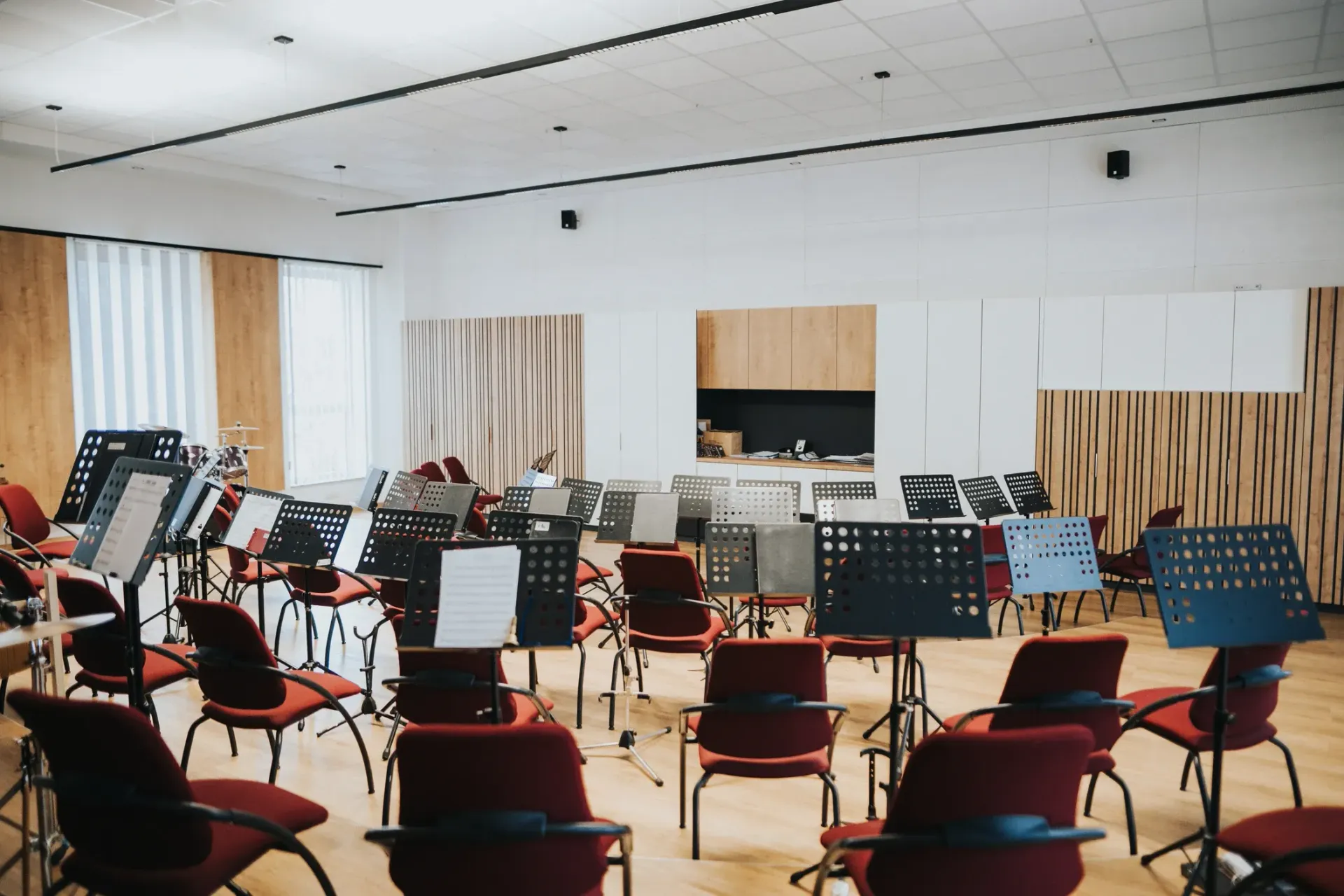 Leerer Probenraum mit einer Wand aus Akustikpaneelen Notenständern und Stühlen, die für ein Orchester aufgestellt sind.