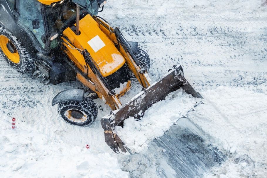 Yellow snowplow clearing snow on a snowy road, viewed from above