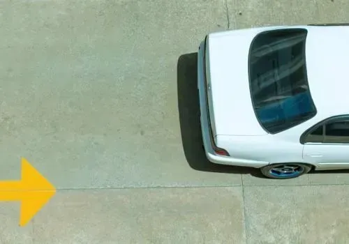 Aerial view of a car driving along a newly marked and cured concrete parking lot in Gracefield.