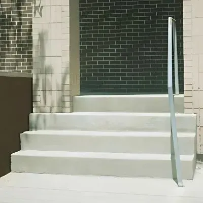 Four new poured cement steps with a handrail installed for a residential complex in Woburn, Lower Hutt.