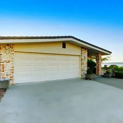 Concrete driveway leading to house and garage with sea view in Belmont.