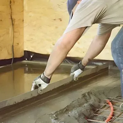 Concrete floor contractor leveling and spreading concrete mix inside a room in Seaview, Lower Hutt.