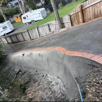 Fresh shotcreted retaining wall with curved profile along a sloped driveway in Maungaraki, Lower Hutt.