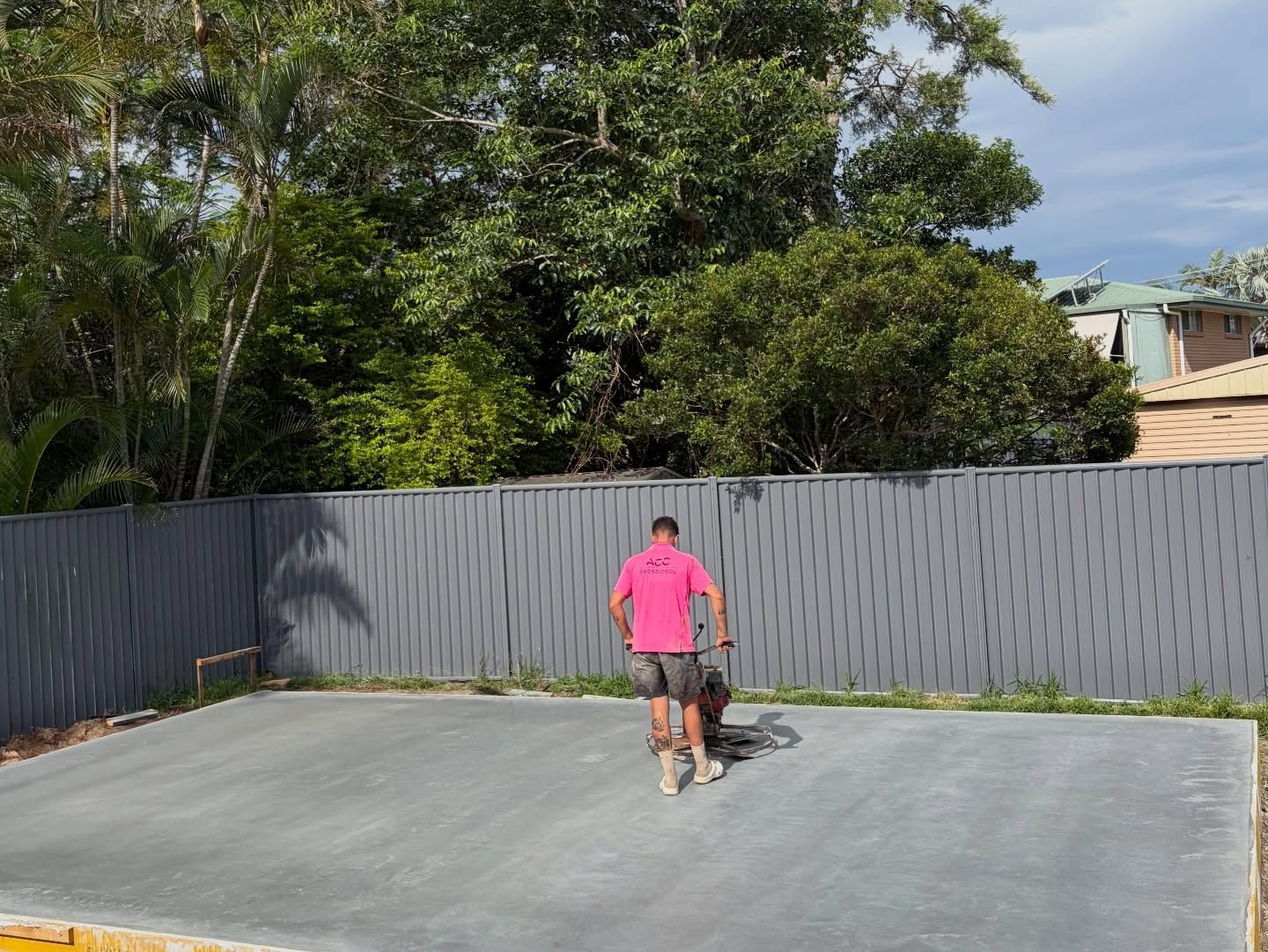 Man in Pink Shirt Walks Across a Concrete Surface, Pulling Something Small — All Concrete Creations in Kingscliff, NSW