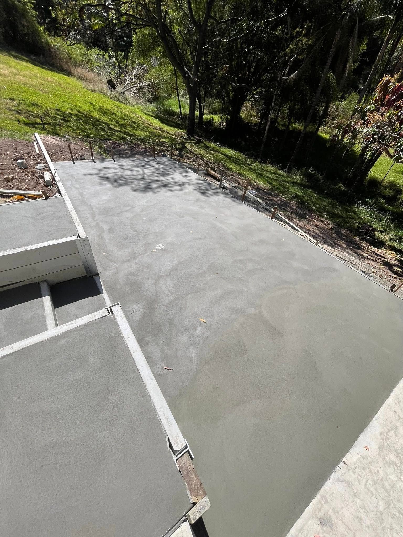 Freshly poured concrete patio with adjacent steps and a sloped, grassy hillside — All Concrete Creations in Kingscliff, NSW