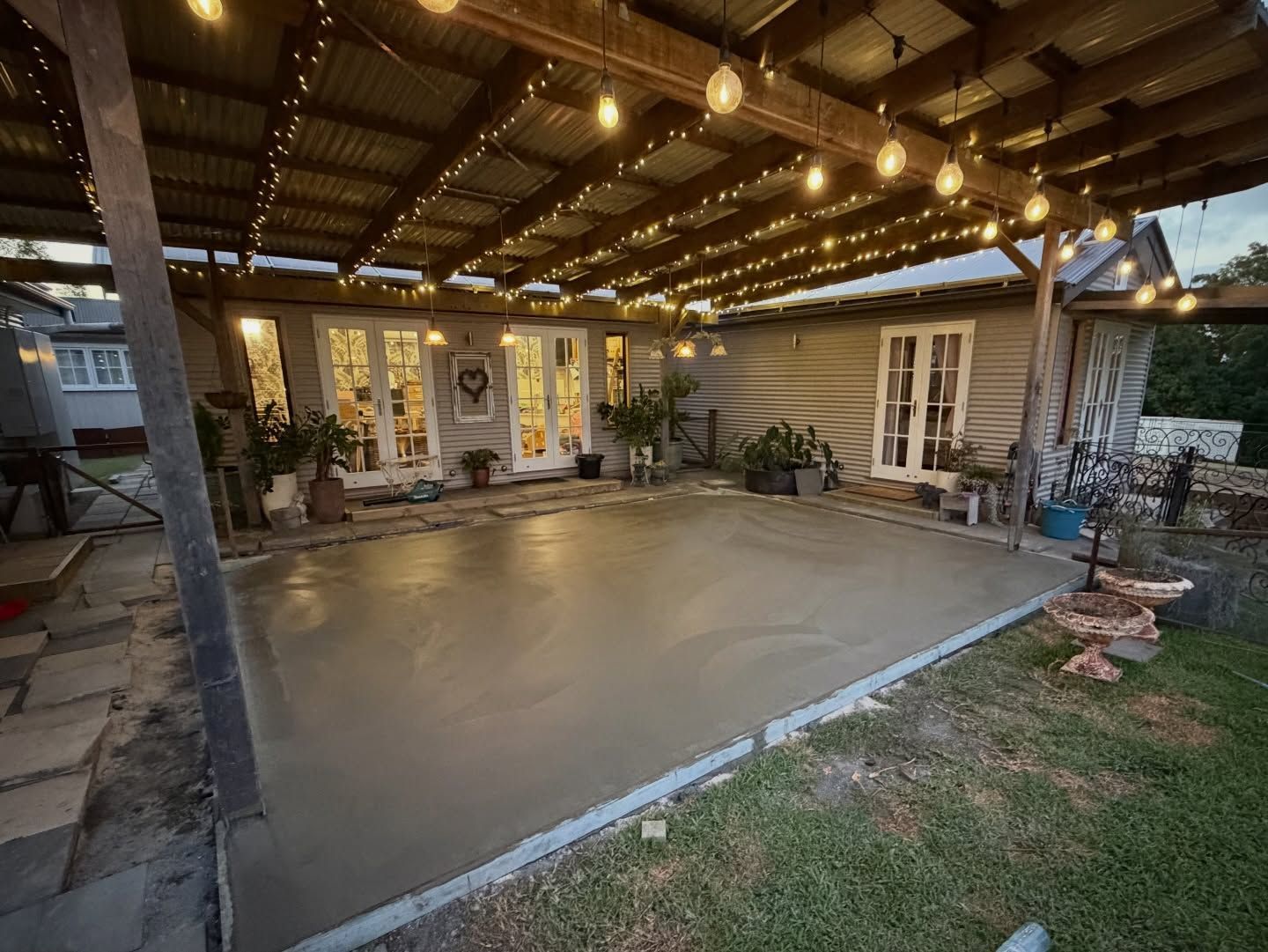 Newly Poured Concrete Patio Under a Corrugated Metal Roof With String Lights — All Concrete Creations in Kingscliff, NSW