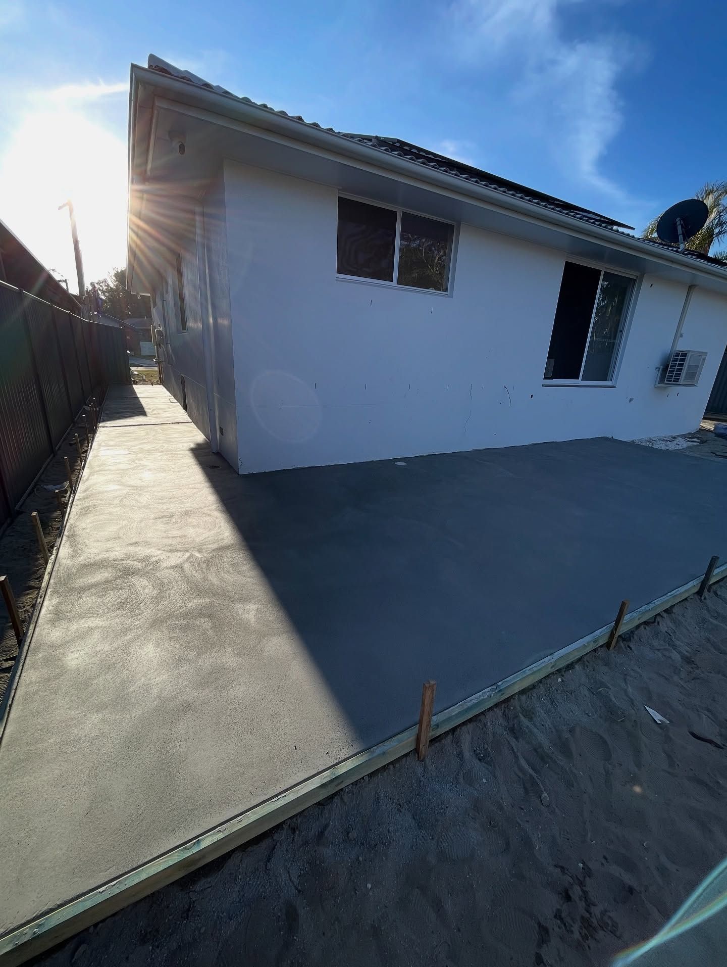 Newly Poured Concrete Patio and Walkway Next to a White House, Bright Sunlight — All Concrete Creations in Byron Bay, NSW