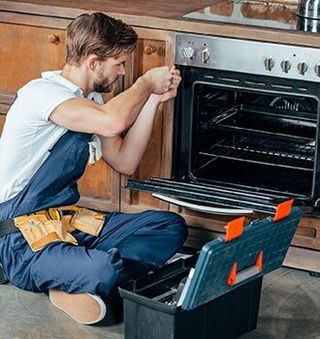 Electric Appliances — Repairman Fixing Oven in Kitchen in Wooster, OH