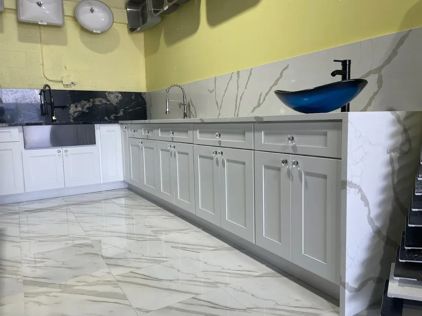 White kitchen cabinets with marble countertops and a blue glass sink.