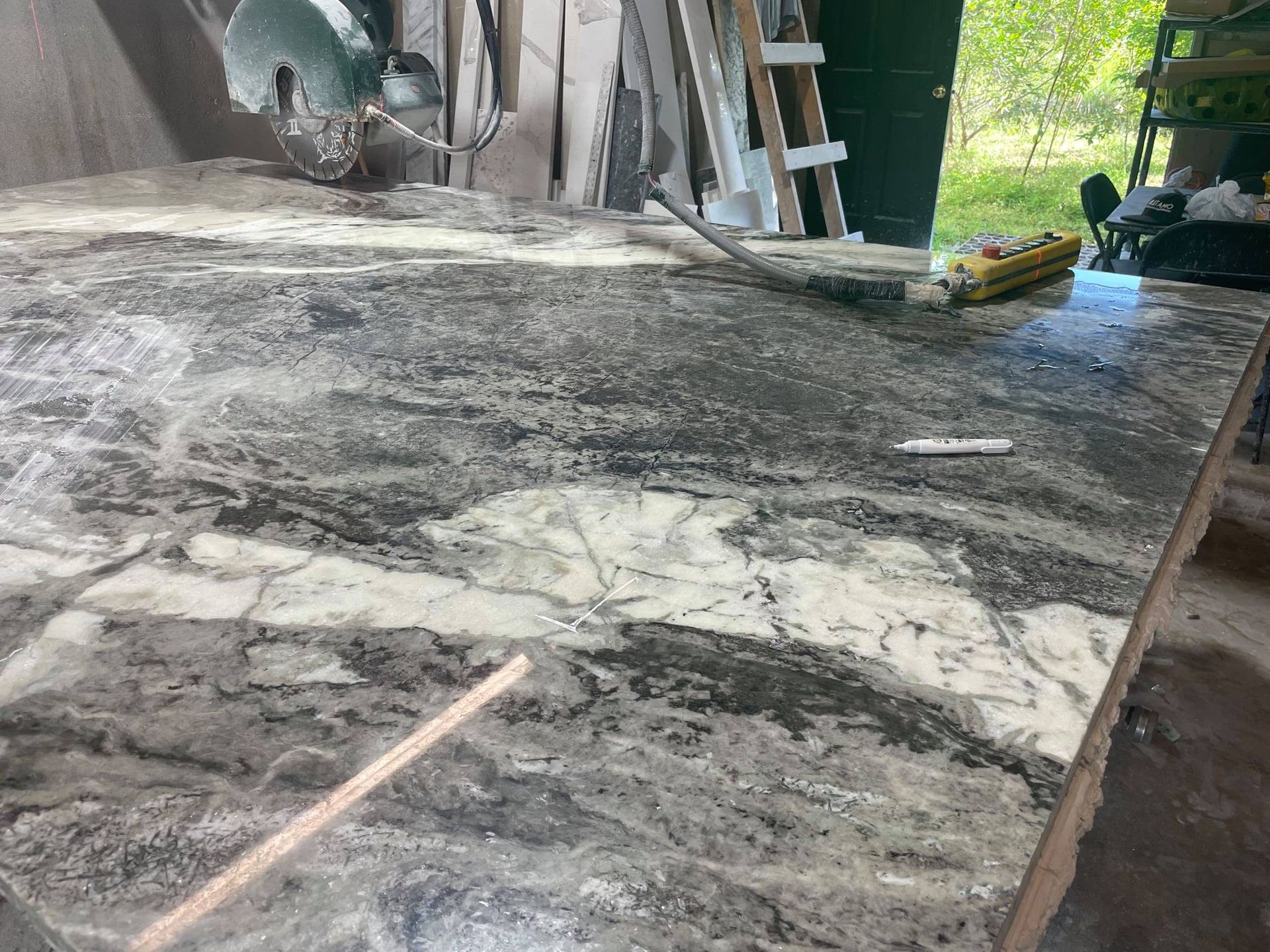 Granite countertop with gray, white, and black veining, on a workbench, with tools.
