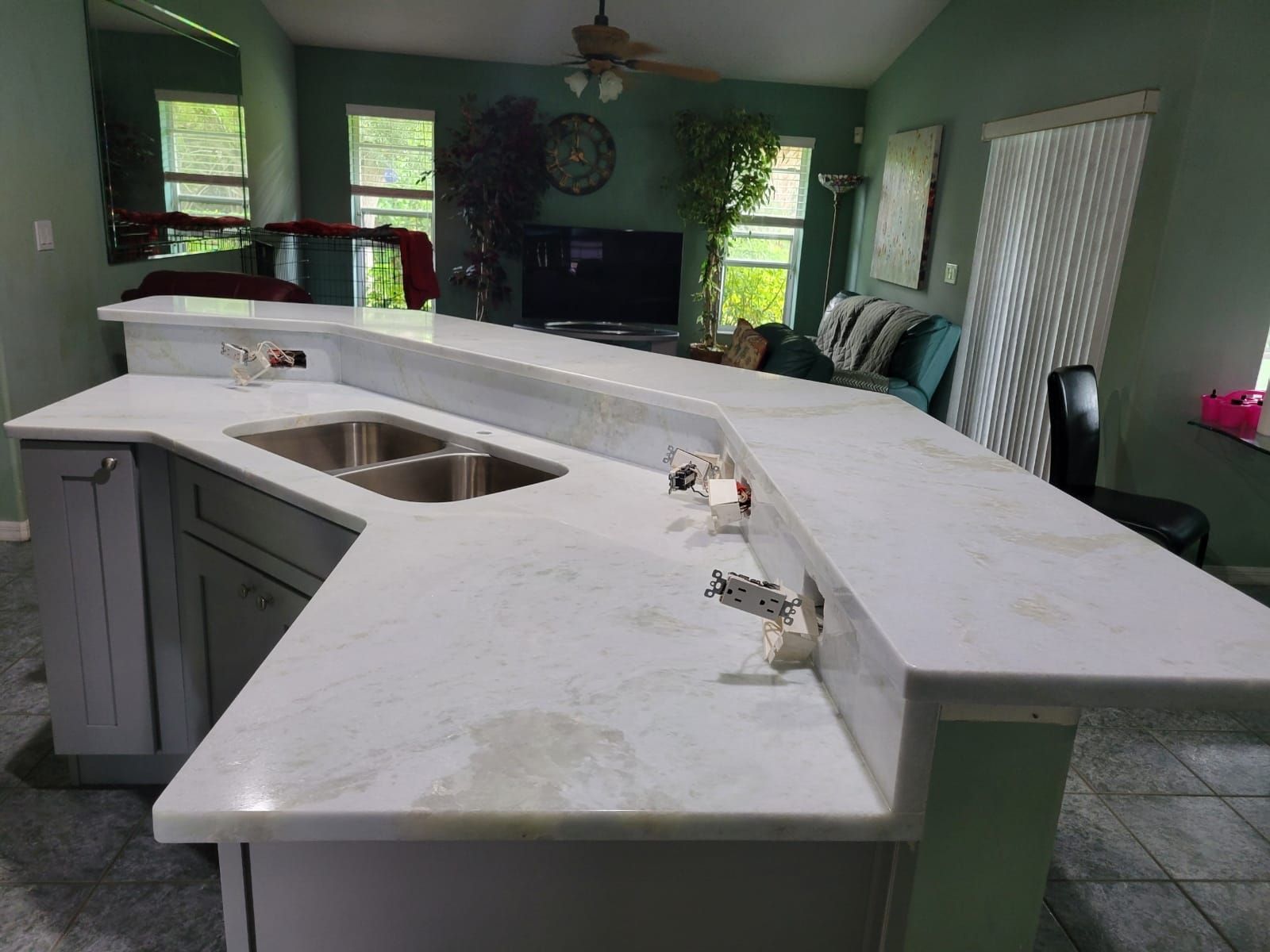 Kitchen island with white countertops, gray cabinets, and a built-in sink.